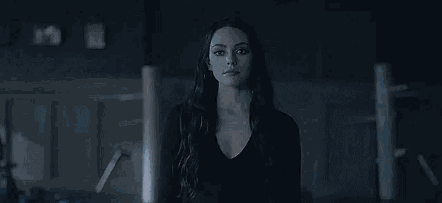 a woman is standing in a dark room with a light coming out of her hand .