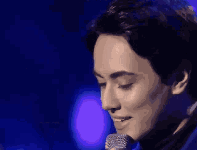 a close up of a man 's face in front of a blue light