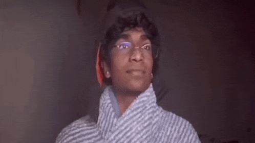 a young man wearing glasses and a striped shirt is looking up at the camera .