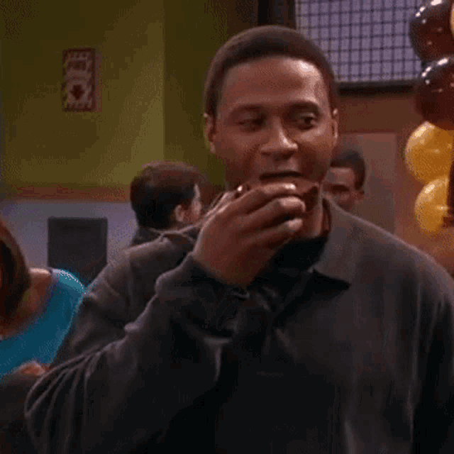 a man is eating an apple in a room with balloons