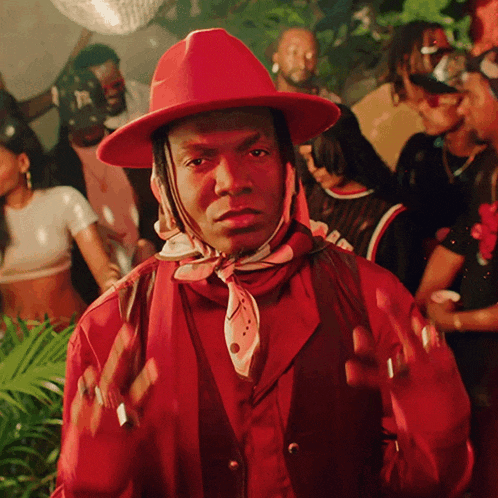 a man wearing a red hat and scarf stands in front of a crowd