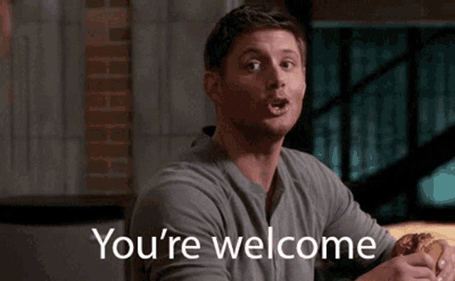 a man is sitting at a table with a sandwich and the words " you 're welcome " on the bottom
