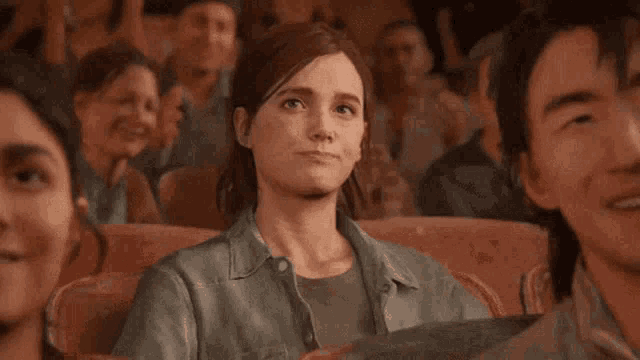 a woman is sitting in a crowd of people watching a movie and clapping her hands .