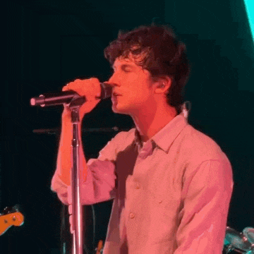 a man is singing into a microphone on a stage in a dark room .