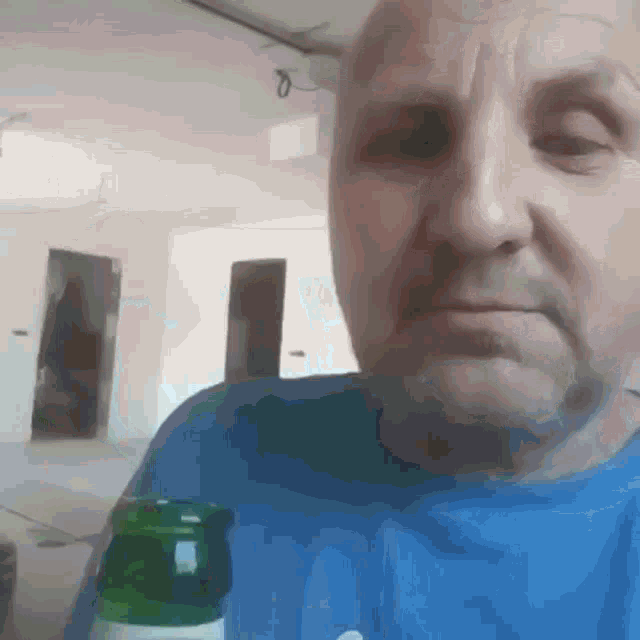 a man in a blue shirt is holding a bottle of beer in his hand .