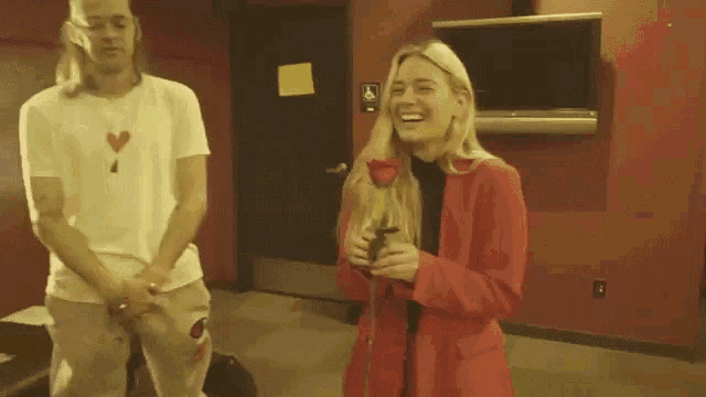 a man and a woman are standing next to each other in a room with a red wall .