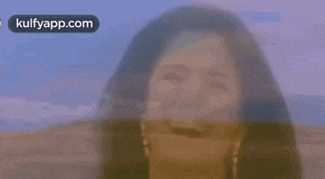 a close up of a woman 's face with a blurred background and a blue sky in the background .