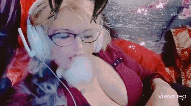 a woman wearing headphones and a cat ear mask is smoking a cigarette .