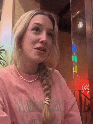 a woman wearing a pink shirt that says manhattan