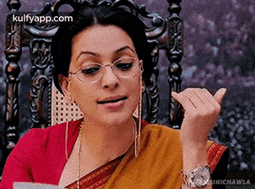 a woman wearing glasses and a watch is sitting in a chair and making a funny face .