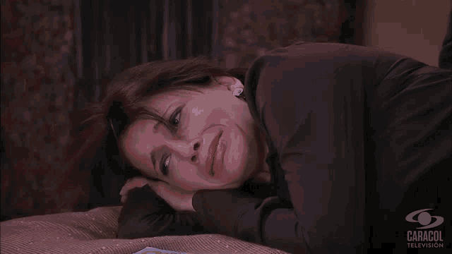 a woman laying on a bed with a caracol television logo in the background