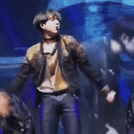 a man in a suit is dancing in front of a crowd on a stage .