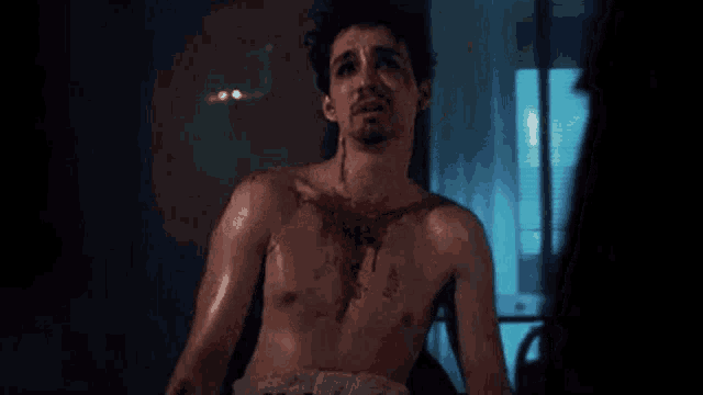 a shirtless man is laying on a bed with blood coming out of his chest .