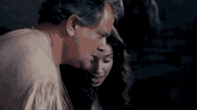 a man and a woman are standing next to each other and the man is kissing the woman on the cheek .