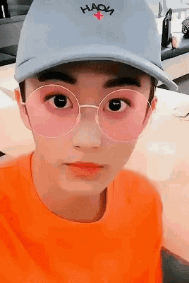 a young man wearing a hat and pink glasses has the word hada on it