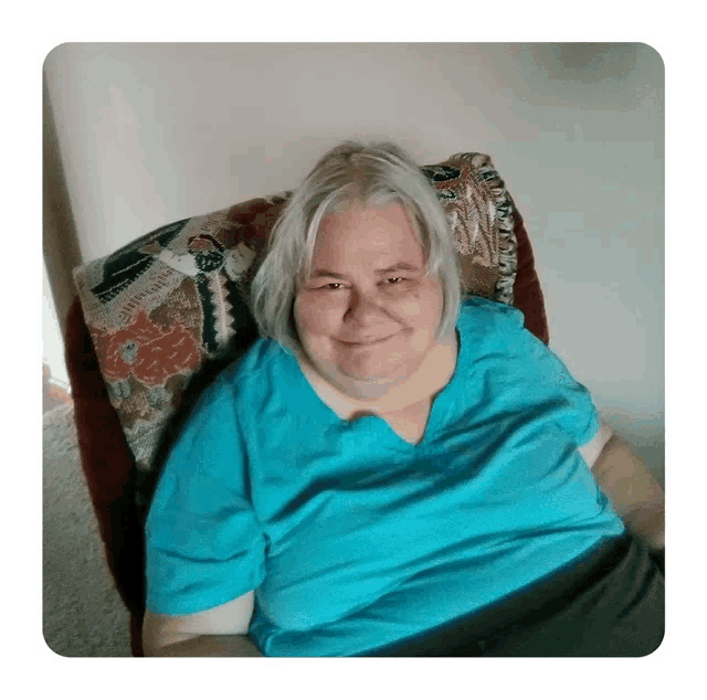 a woman in a blue shirt is sitting in a chair and smiling