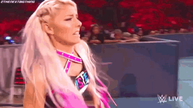 a female wrestler is standing in front of a crowd .