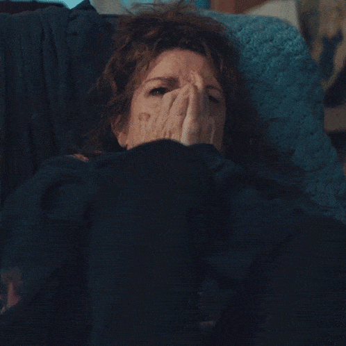 a woman laying on a couch with her eyes closed and her hands on her face