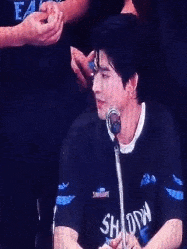 a man is sitting in front of a microphone wearing a black shirt .