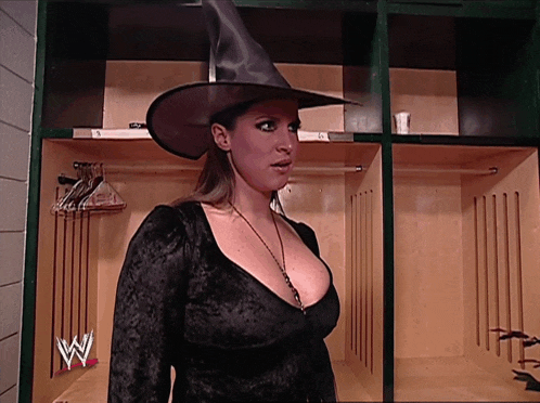 a woman in a witch costume is in a locker room with a w logo on the wall