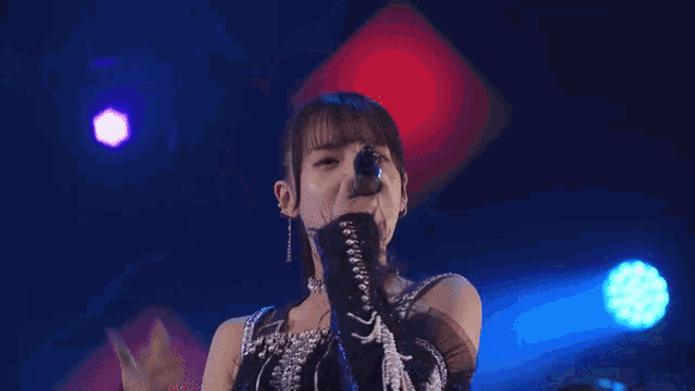 a woman is singing into a microphone on stage