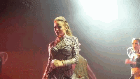 a woman in a silver and black outfit is standing on stage