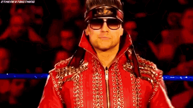 a man in a red jacket and sunglasses is standing in a ring .