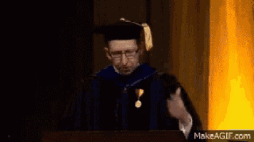 a man in a graduation cap and gown giving a speech