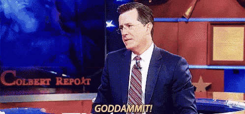 a man in a suit and tie is standing in front of a television screen and says goddammit .