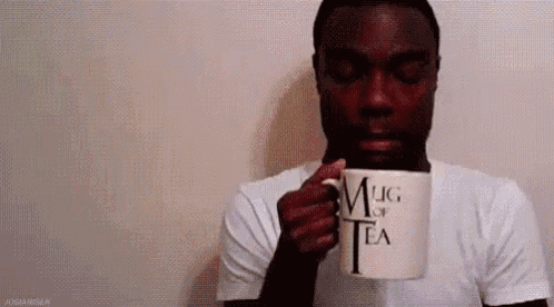 a man is holding a mug of tea in his hand .