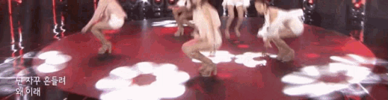 a group of women are dancing on a red stage with chinese writing on the bottom