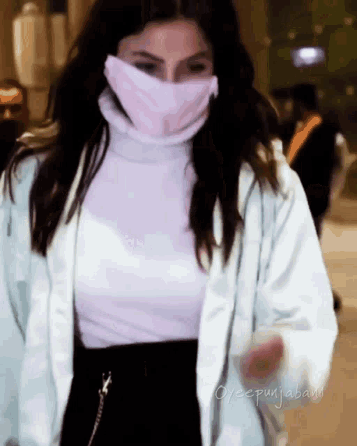 a woman wearing a pink face mask and a white jacket has the name oyeepunjaband written on the bottom right