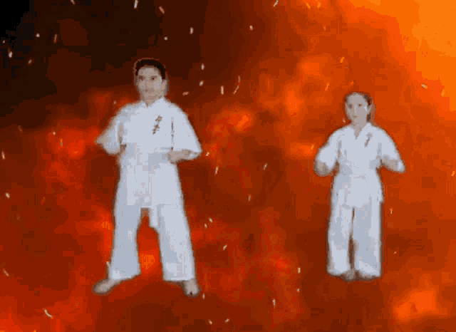 a man and a woman in karate uniforms are standing in front of a fire