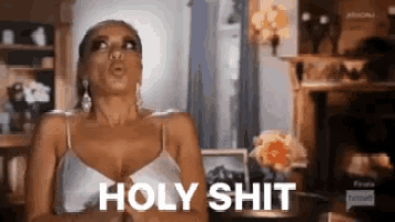 a woman in a white tank top is making a funny face and says holy shit