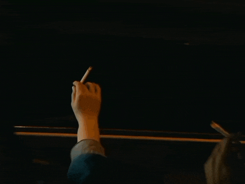 a person 's hand is visible in the dark with a street light in the background