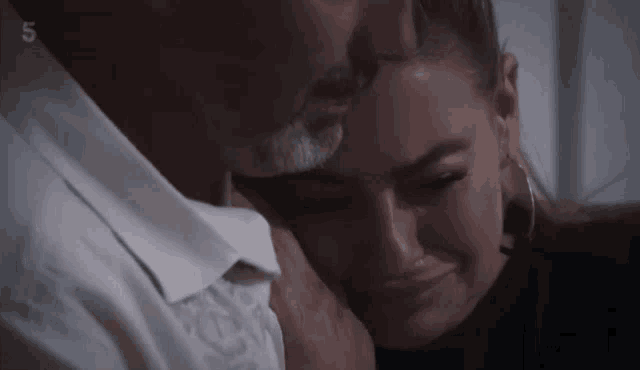 a man with a beard is hugging a woman who is crying with the number 5 above them