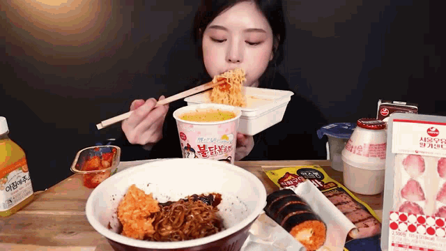 a woman is eating noodles with chopsticks from a cup that says ramen