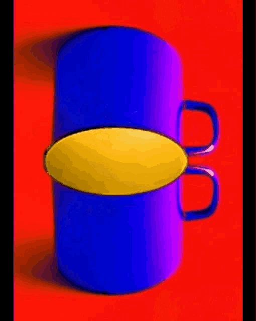 a blue cup with a yellow circle in the middle is sitting on a red surface .