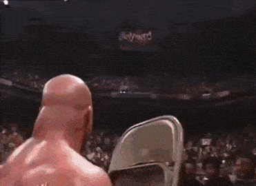 a wrestler is holding a chair in a wrestling ring .
