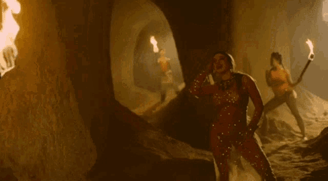 a naked woman is dancing in a cave with a torch in her hand .