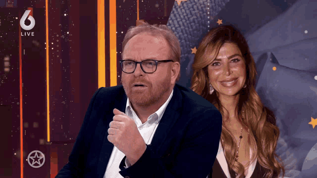 a man and a woman are sitting in front of a live 6 sign