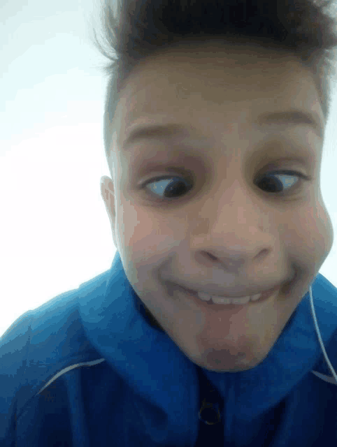 a boy wearing a blue jacket makes a funny face