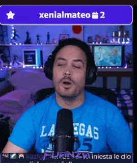 a man wearing headphones and a blue shirt that says la egas 05 singing into a microphone