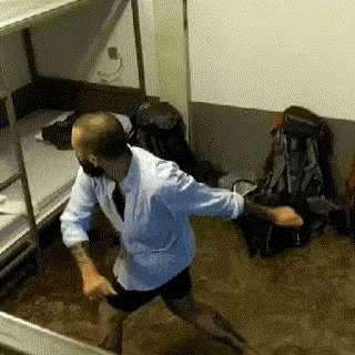 a man in a white shirt and tie is dancing in a room with bunk beds and backpacks