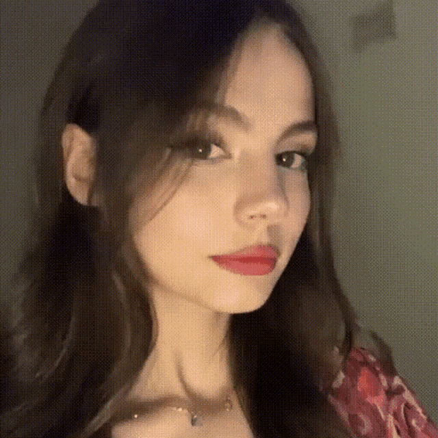 a close up of a woman 's face with long black hair and red lips .