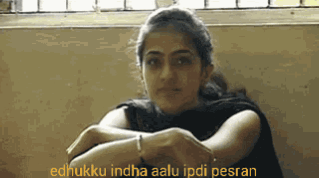 a woman is sitting with her arms crossed and the words " edhukku indha aalu ipdi pesran " behind her