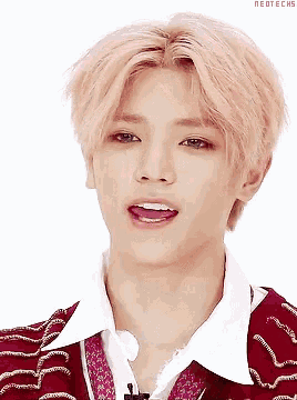 a close up of a young man with pink hair wearing a white shirt and a red sweater .