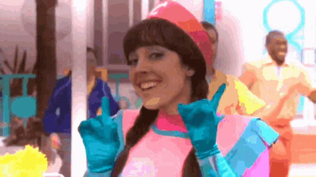 a woman in a pink and blue costume is giving a thumbs up
