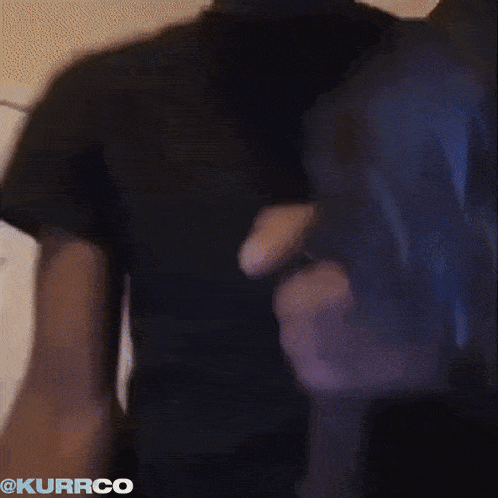 a man in a black shirt is holding a microphone with the word kurrco on the bottom right