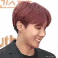 a close up of a man with red hair wearing a black suit and smiling .